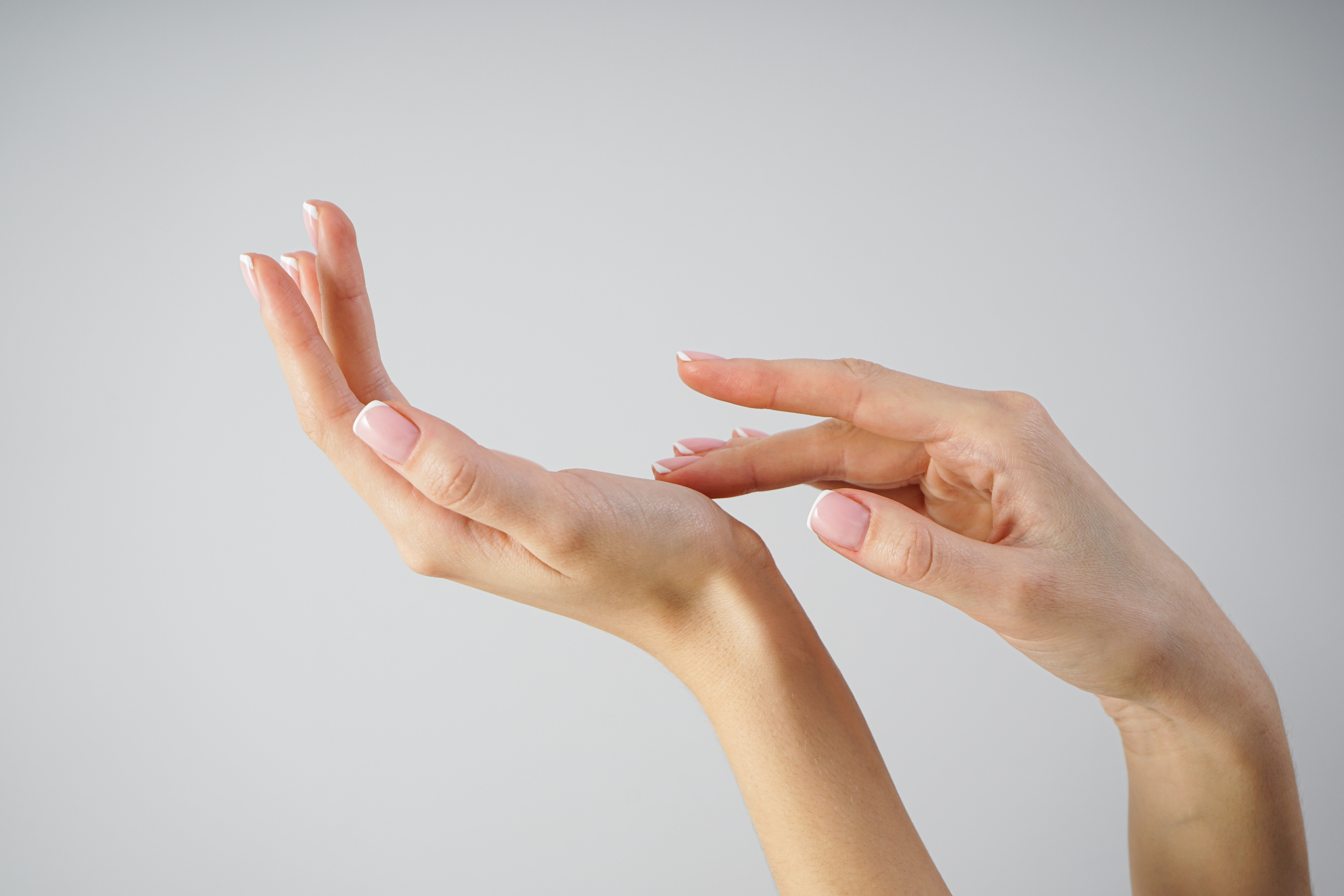 pair of healthy female hands with one hand touching the palm of the other