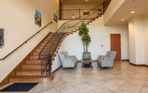 Spacious lobby entrance featuring a wooden staircase and seating area at the Monterey practice of the best plastic surgeon, Dr. David T. Morwood.