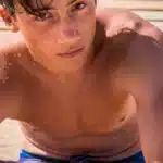 boy sitted on the sand and on the wood at the beach